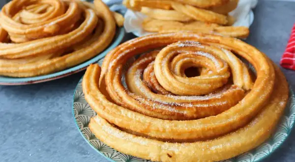 Churros dorados y azucarados en espiral en platos.