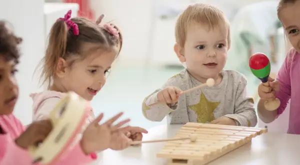 Kinder unter 3 Jahren musizieren fröhlich mit Xylophon und Maracas.