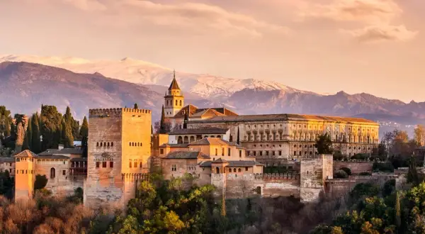 Die Alhambra in Granada, ein Ort voller Geschichte und **Granada Geheimtipps**, thront vor schneebedeckten Bergen.