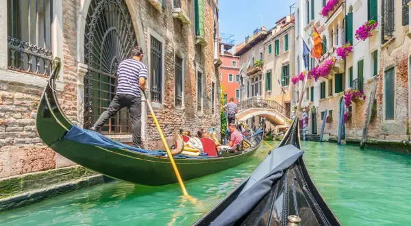 En gondoltur i Venedig är en dröm för många. Undrar du vad kostar det att åka gondol i Venedig? Här ser du en gondol som glider fram på kanalen.