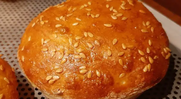 Un pain à burger maison doré et moelleux, parsemé de graines de sésame.