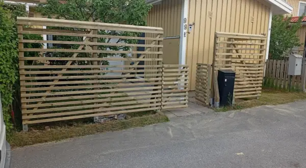 Nya trästaket byggs för att bygga insynsskydd vid ett gult hus.