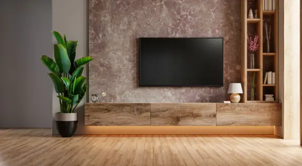 Soggiorno moderno con TV a parete, mobile in legno e una grande pianta. La parete di fondo ha una texture che ricorda una pittura sabbiata, un dettaglio che influisce sul pittura sabbiata prezzo.