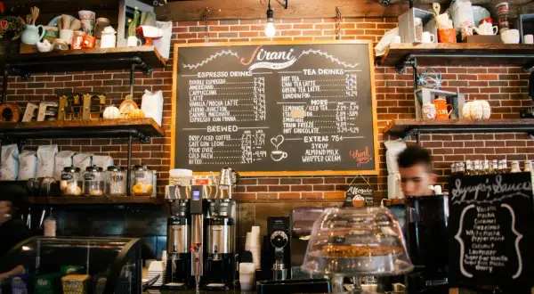 Pizarra con lista de precios de bebidas para bares, incluyendo cafés, tés y extras. ¡Una guía útil para la lista de precios de bebidas para bares 2026!