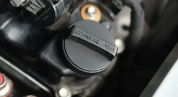 Czarna zakrętka silnika z napisem "ENGINE OIL" i ikonką poziomu oleju. Czas na wymianę zużytego oleju.