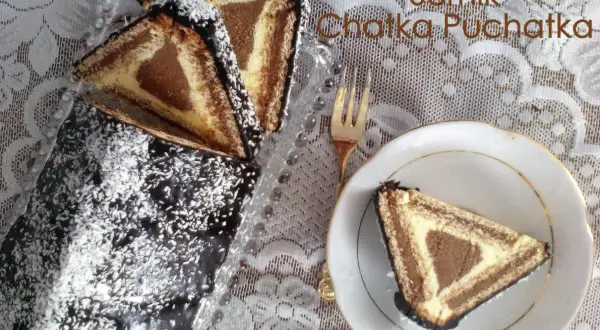 Ciasto "Chatka Puchatka" z polewą czekoladową i wiórkami kokosowymi. Na talerzyku kawałek ciasta w kształcie trójkąta.
