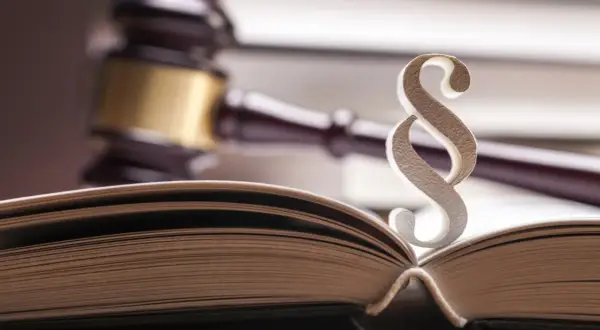 Otwarta księga prawa, paragraf i młotek sędziowski – symbole sprawiedliwości i arbitrażu.