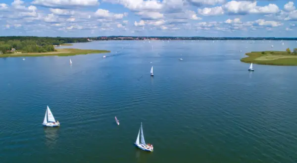 Segelboote auf dem Wasser in Masuren, Polen. Ein sonniger Tag mit Wolken, ideal zum Segeln.