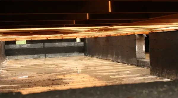 Fundament pod słupy drewniane, z bloczków betonowych, z wilgotną ziemią i drewnianym stropem.