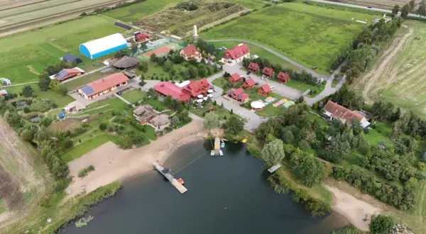 Malownicza jeziorna osada Gnojewo z piaszczystą plażą, pomostami i licznymi budynkami wypoczynkowymi.