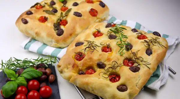 Två gyllene focaccia med tomater, oliver och rosmarin. Ett perfekt focaccia recept från Zeina som ser ljuvligt ut!