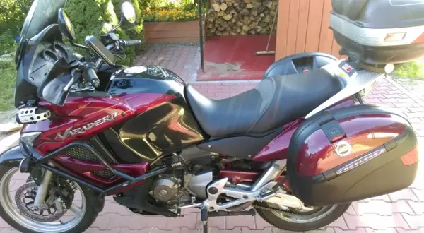 Czerwony motocykl Honda Varadero 1000 z kuframi, zaparkowany na podjeździe.