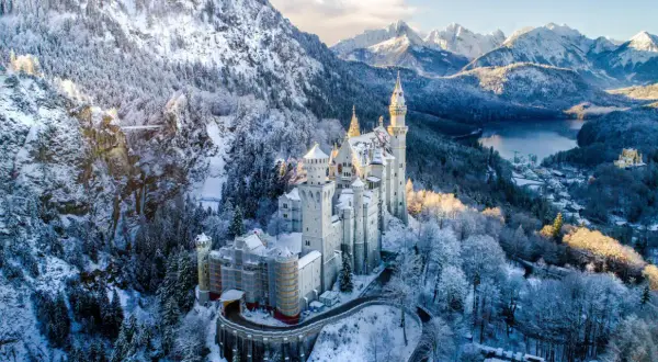 Schloss Neuschwanstein im winterlichen Glanz, ein märchenhafter Ort für einen Urlaub im Dezember. Schnee bedeckt die Berge und Bäume.