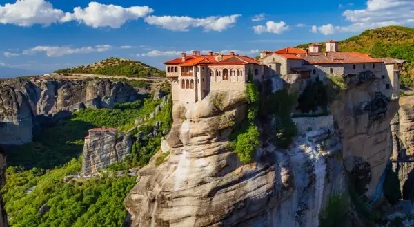 Meteora Kloster, ein atemberaubendes Bauwerk auf Felsen, thront majestätisch über einer grünen Schlucht.