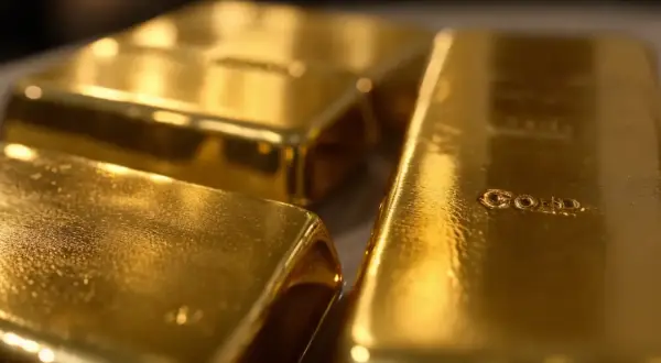 Trzy błyszczące sztabki złota, jedna z napisem "GOLD".