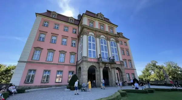 Zamek Książ, malowniczo położony, łatwy dojazd PKP. Turyści zwiedzają barokową budowlę w słoneczny dzień.
