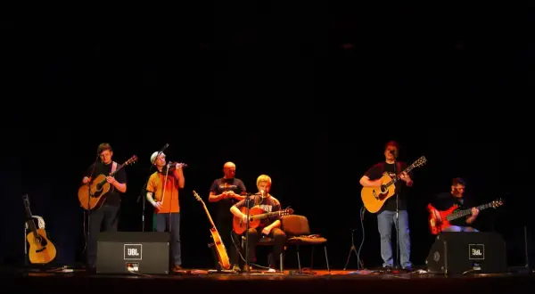 Zespół gra na gitarach i skrzypcach. W tle słychać **stare dobre małżeństwo utwory**.