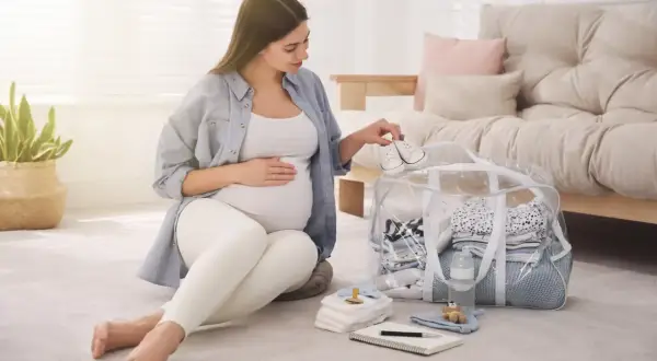 Przyszła mama przygotowuje torbę do porodu, układając maleńkie buciki na wierzchu.
