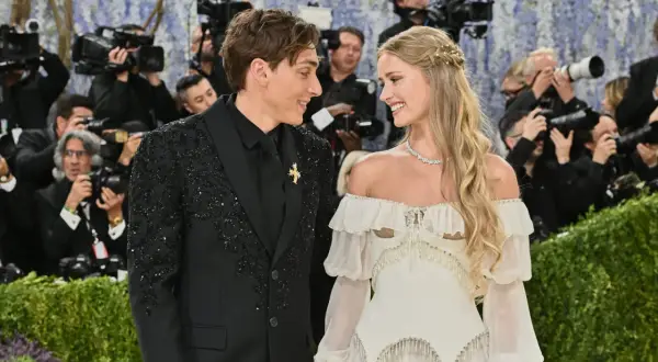 Desiré Inglander och hennes partner ler mot varandra omgivna av fotografer.