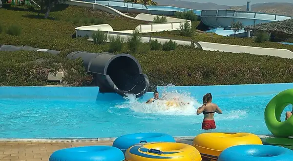 ¡Diversión en el parque Mario Park! Niños se deslizan por toboganes acuáticos y chapotean en la piscina con flotadores coloridos.