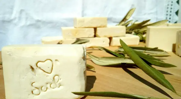 Sapone artigianale, frutto della saponificazione olio di oliva, con decorazione a cuore e scritta "Sich". Foglie d'ulivo completano la scena.