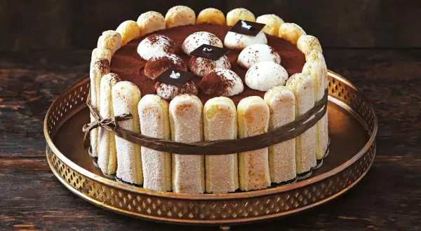 Ein köstliches, original italienisches Tiramisu-Torte, umrandet von Löffelbiskuits und verziert mit Kakao und Schokolade.