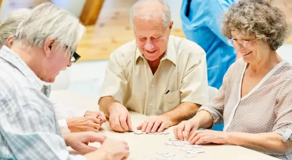 Des résidents d'un EHPAD participent à un atelier cognitif, assemblant un puzzle.
