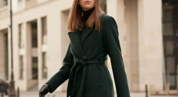 Elegancka kobieta w ciemnozielonym płaszczu z paskiem. Dowiedz się, jak prać płaszcz z wełny i poliestru, by zachował swój kształt.
