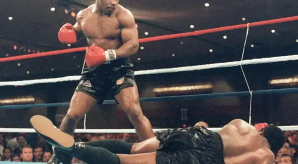 Mike Tyson står över en liggande motståndare i ringen. Hans imponerande fysik visar varför mike tyson vikt var så avgörande.