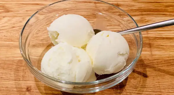 Schüssel mit drei Kugeln Milcheis ohne Sahne, perfekt zum milcheis ohne sahne selber machen. Löffel liegt daneben.