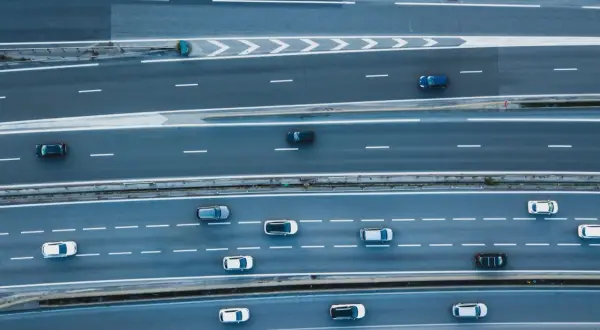 Widok z góry na autostradę, gdzie samochody wykonują manewry **wymijania** i **omijania** przeszkód, tworząc dynamiczny obraz ruchu drogowego.
