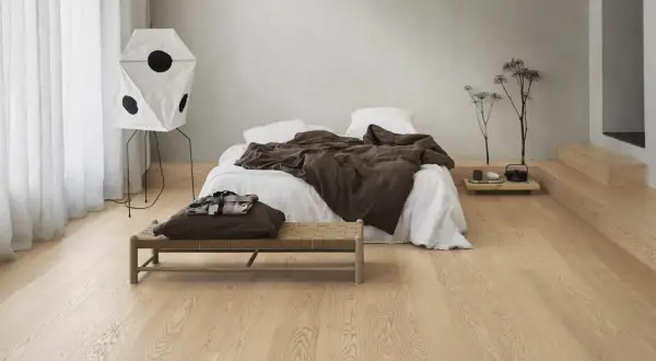 Sovrum med en säng, en bänk och en unik lampa. Olika golv i olika rum skapar en varm och inbjudande atmosfär.