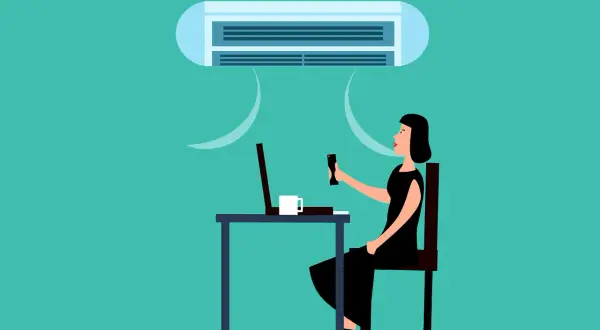 Une femme ajuste la climatisation pour une température idéale au bureau, profitant d'un environnement de travail confortable.