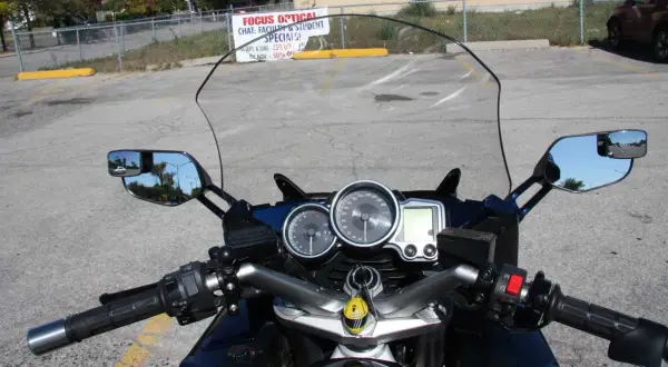 Widok z motocykla: przedłużenie lusterek motocyklowych, deska rozdzielcza z prędkościomierzem i obrotomierzem.