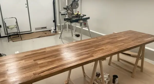 Långt ekbord på sågbockar, redo att behandla ekbordet. Kap- och geringssåg i bakgrunden.