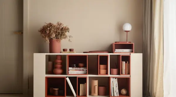 Nowoczesna biblioteczka z elementami w kolorze terakota, wypełniona książkami i dekoracjami.