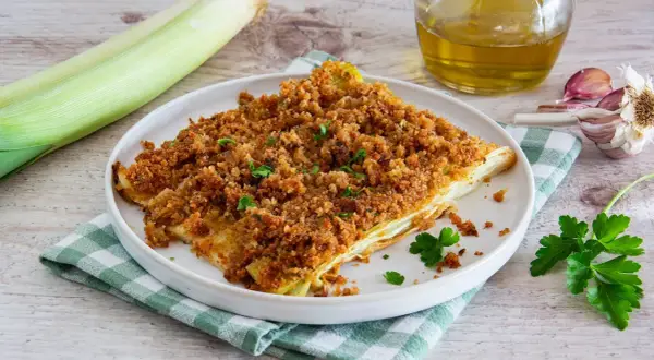 Porro al forno croccante e dorato, servito su un piatto bianco con un contorno di prezzemolo fresco.
