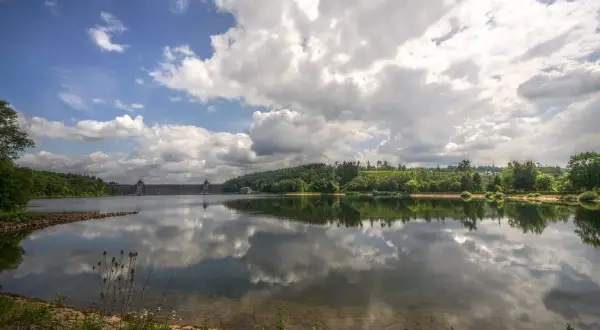 Stausee mit imposanter Staumauer, gespiegelt im ruhigen Wasser. Ein idyllischer Anblick, seen in NRW.
