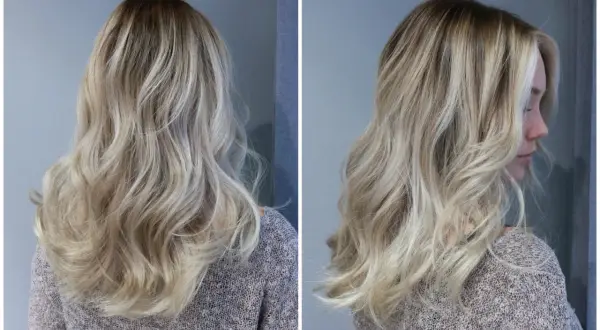 En kvinna med vackert, vågigt hår i en "old money blonde"-nyans. Håret har en naturlig, solkysst look med ljusa slingor.