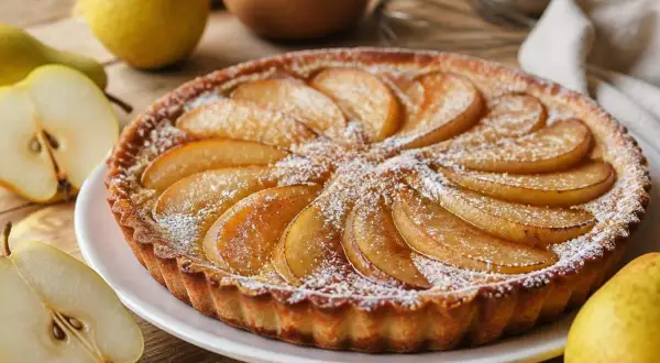 Une délicieuse tarte aux poires, saupoudrée de sucre glace, est présentée sur une assiette blanche. Des poires fraîches sont disposées autour.