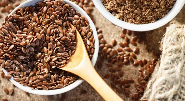 Schüssel mit ganzen Leinsamen und gemahlenen Leinsamen. Leinsamen roh essen ist gesund!