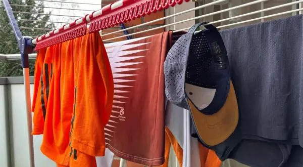 Wäscheleine mit Kleidung, darunter eine orangefarbene Sportbekleidung und eine Kappe zum Reinigen.
