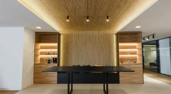 Modern office interior with a wall covered in vertical wood slats, demonstrating como poner listones de madera en la pared.