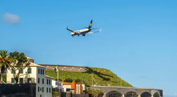Samolot Ryanair ląduje na lotnisku na Maderze, nad budynkami i basenem z delfinem.