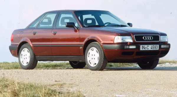 Roter Audi 80 B4 Limousine von vorne rechts auf Schotterweg.