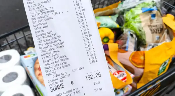Kassenbon mit vielen Produkten, Einkaufswagen im Hintergrund. Die Digitalisierung im Handel wird durch solche Belege und die Möglichkeit zur digitalen Erfassung von Einkäufen sichtbar.