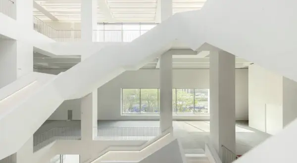 Wnętrze nowego muzeum sztuki nowoczesnej w Warszawie. Białe, geometryczne schody i przestrzenie tworzą nowoczesną architekturę.