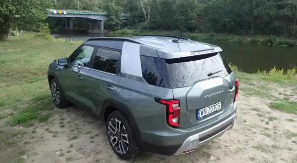 Zielony Torres auto zaparkowany nad rzeką, w tle most i las.