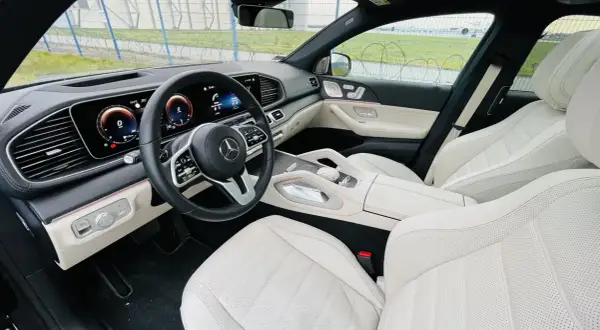 Wnętrze luksusowego Mercedesa GLE 400d z jasną, skórzaną tapicerką i nowoczesnym kokpitem.