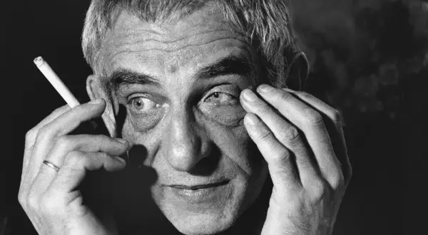 Portret Krzysztofa Kieślowskiego, reżysera, z papierosem w dłoni. Jego filmy, jak "Dekalog", poruszają głębokie tematy.